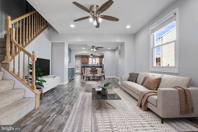 living room featuring a ceiling fan, stairway, wood finished floors, and baseboards