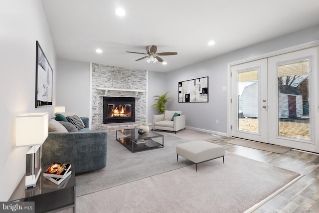 living room with a large fireplace, baseboards, french doors, light wood-type flooring, and recessed lighting