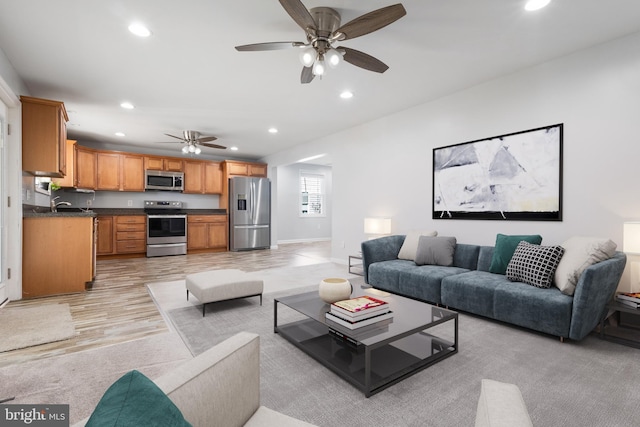 living room with baseboards, ceiling fan, light wood finished floors, and recessed lighting