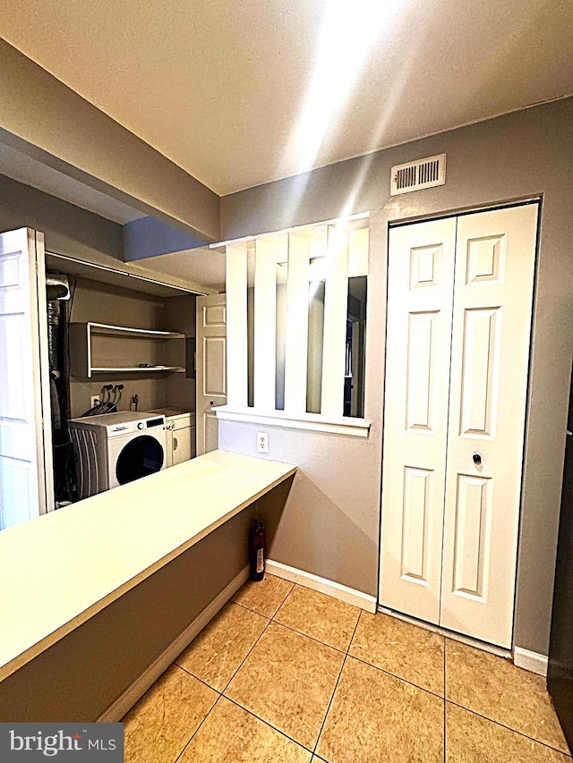 bathroom featuring tile patterned flooring, visible vents, washer and clothes dryer, and baseboards