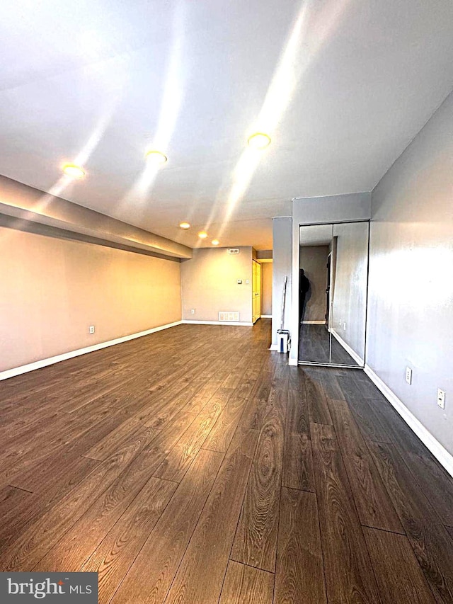 below grade area featuring baseboards, visible vents, and dark wood finished floors