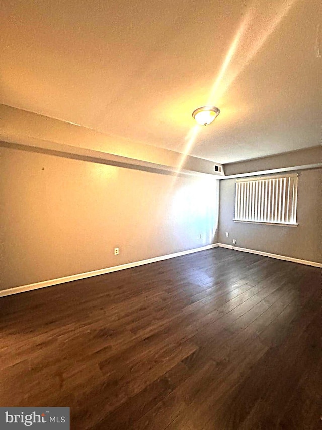 empty room featuring dark wood finished floors, a textured ceiling, and baseboards