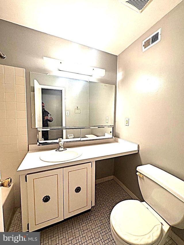 full bathroom featuring toilet, vanity, and visible vents