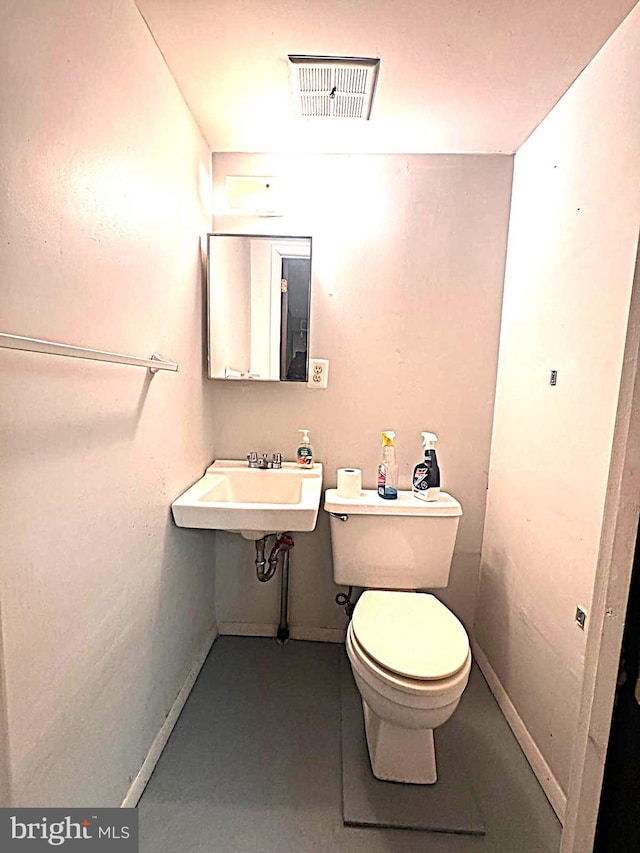 bathroom featuring toilet, baseboards, visible vents, and a sink