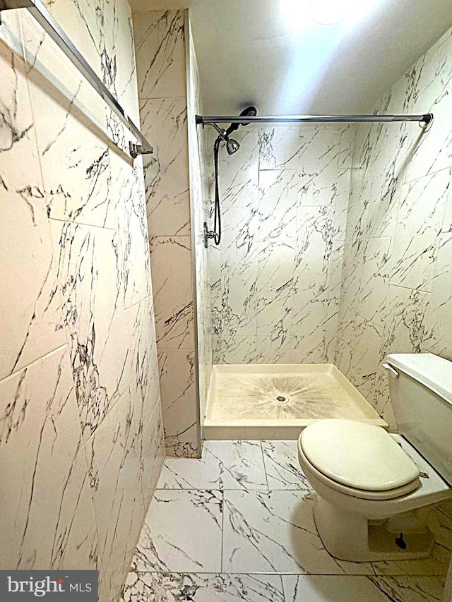 full bathroom featuring toilet, marble finish floor, and a shower stall