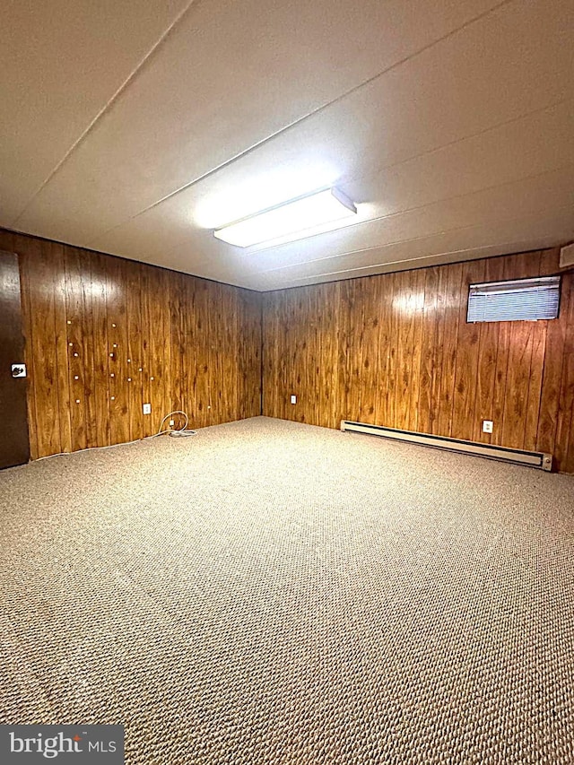 finished basement featuring wood walls, baseboard heating, and carpet flooring