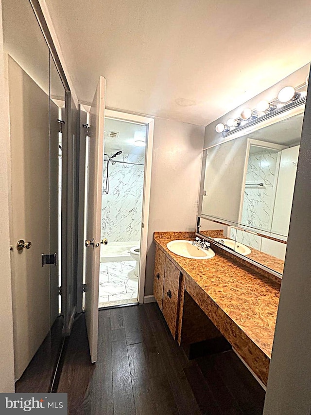 full bathroom featuring a marble finish shower, hardwood / wood-style floors, and vanity