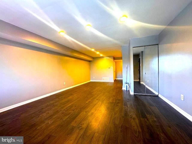 interior space with dark wood-style floors, visible vents, and baseboards