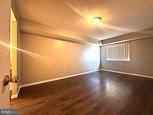 spare room featuring dark wood-style flooring and baseboards