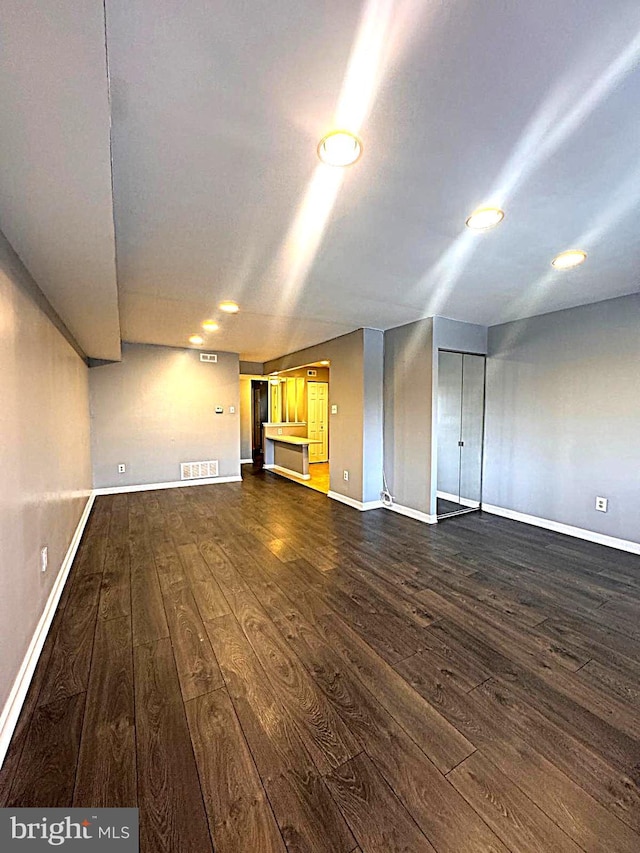 spare room featuring dark wood-style flooring, visible vents, and baseboards