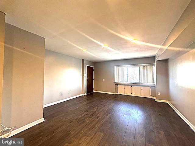 unfurnished room featuring dark wood-style flooring and baseboards