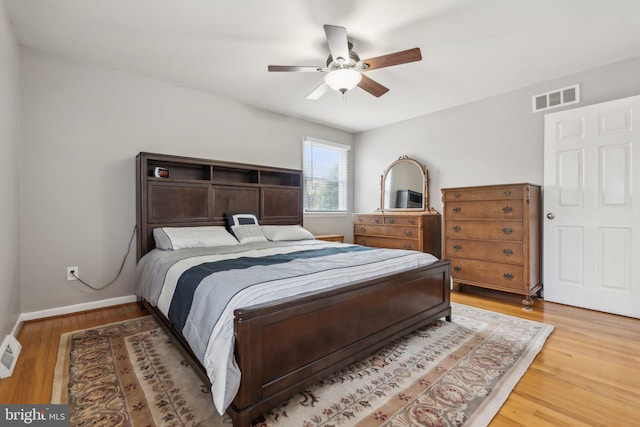 bedroom featuring light wood-style floors, baseboards, visible vents, and a ceiling fan