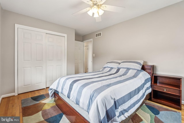 bedroom featuring ceiling fan, a closet, visible vents, and wood finished floors