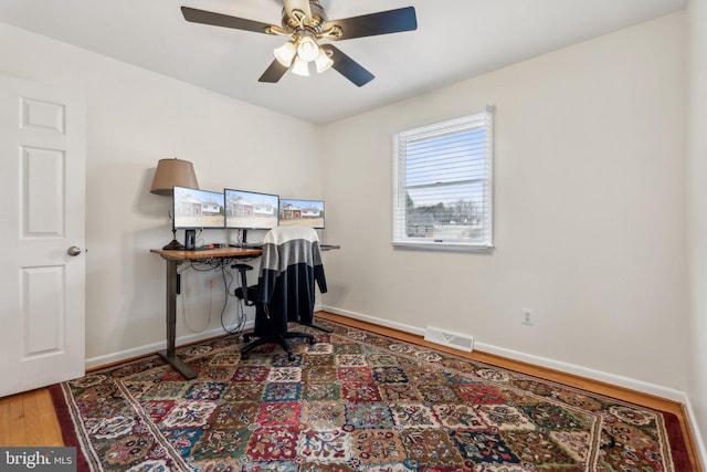 office featuring a ceiling fan, wood finished floors, visible vents, and baseboards