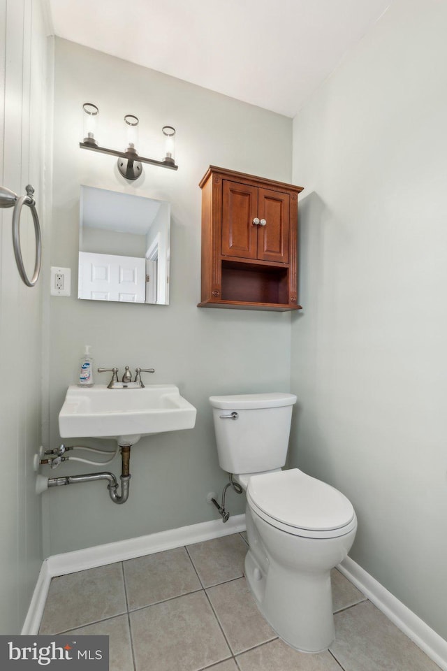 half bathroom featuring baseboards, toilet, and tile patterned floors