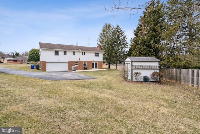 rear view of house featuring a yard, brick siding, fence, and a shed