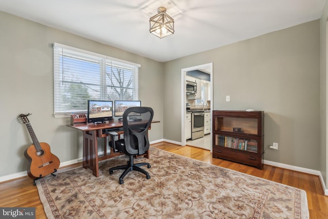 home office with a sink, baseboards, and wood finished floors