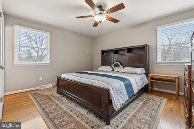 bedroom featuring light wood-style floors, baseboards, multiple windows, and visible vents