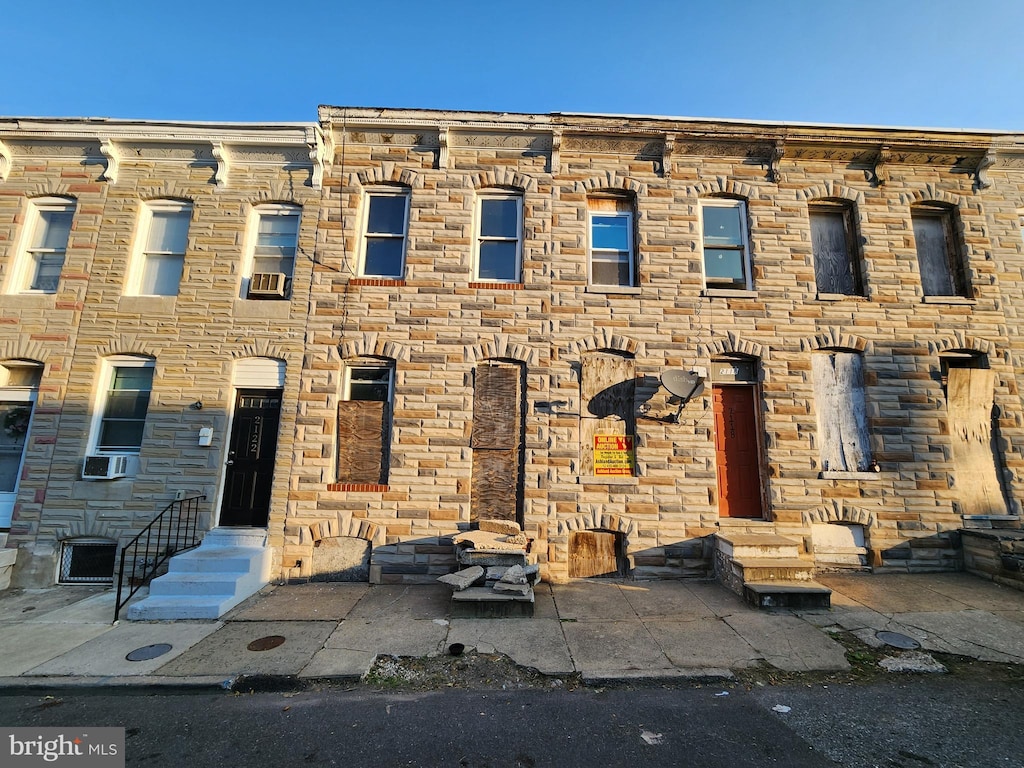 view of property featuring entry steps, stone siding, and cooling unit