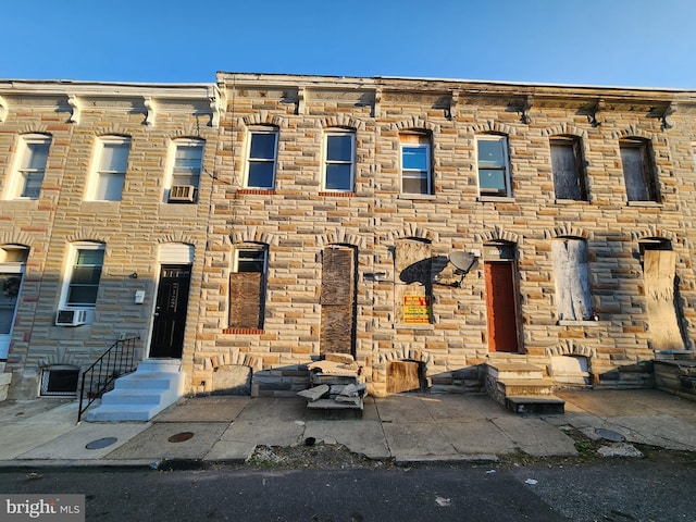 view of property featuring entry steps, stone siding, and cooling unit