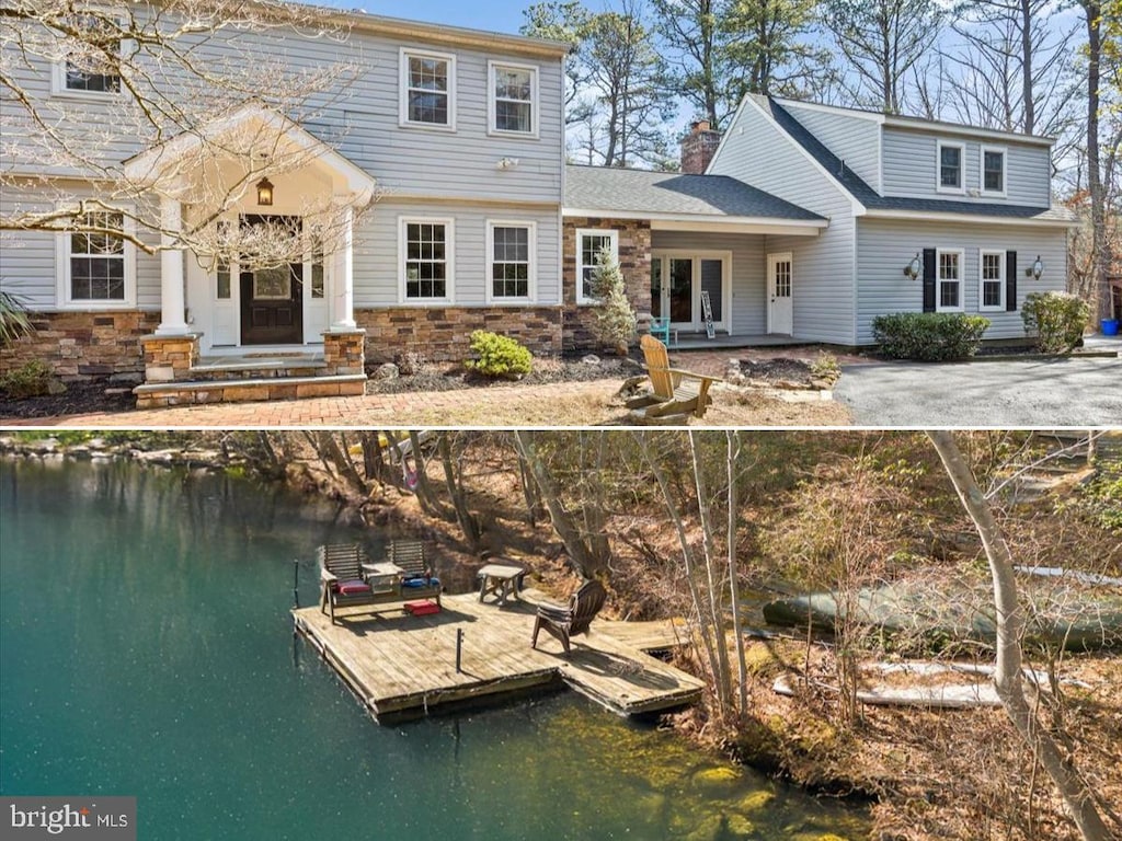 back of house featuring entry steps, stone siding, a water view, and a chimney