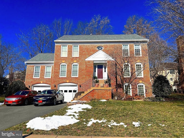 view of front of house with a garage, driveway, brick siding, and a front lawn