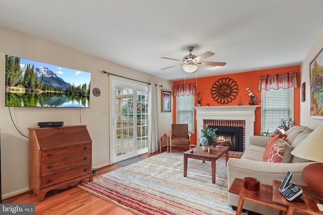 living room with a healthy amount of sunlight, ceiling fan, a fireplace, and wood finished floors