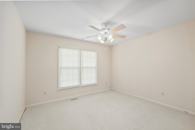 empty room featuring light carpet, ceiling fan, visible vents, and baseboards