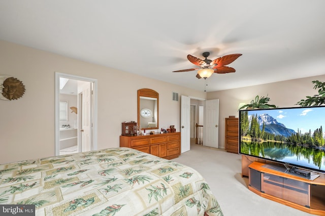 bedroom featuring a ceiling fan, ensuite bath, visible vents, and light colored carpet