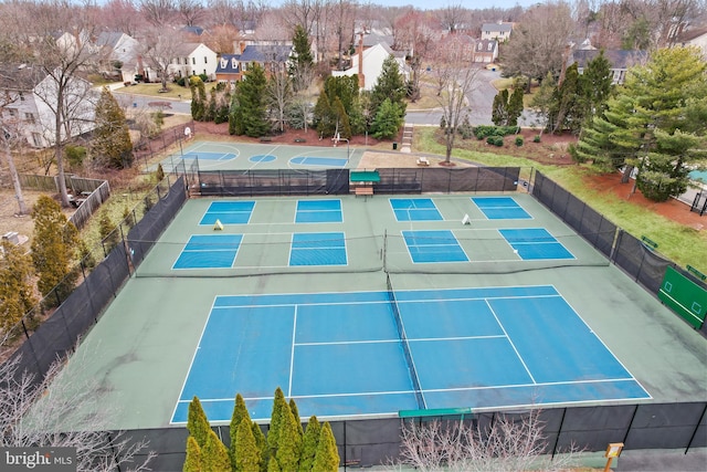 view of tennis court featuring a residential view and fence