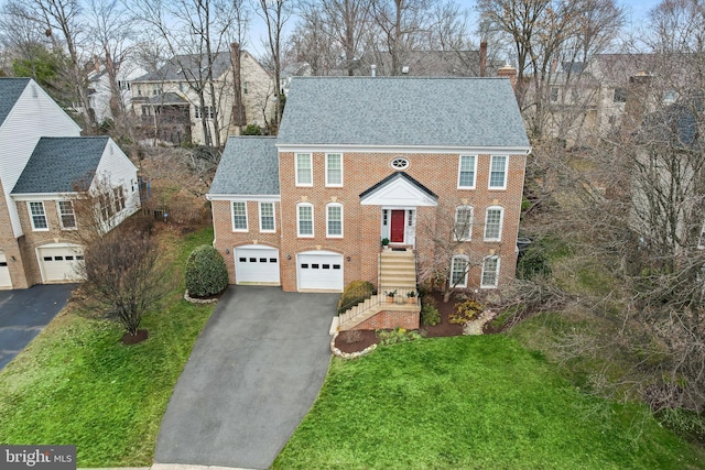 view of front of home with aphalt driveway, brick siding, a chimney, and an attached garage