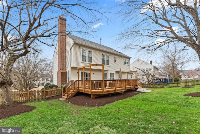 rear view of house with a deck, a fenced backyard, a lawn, and a chimney