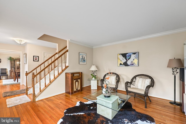 living area featuring wood-type flooring, stairs, ornamental molding, and baseboards