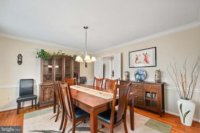 dining room with light wood finished floors, crown molding, baseboards, and a notable chandelier