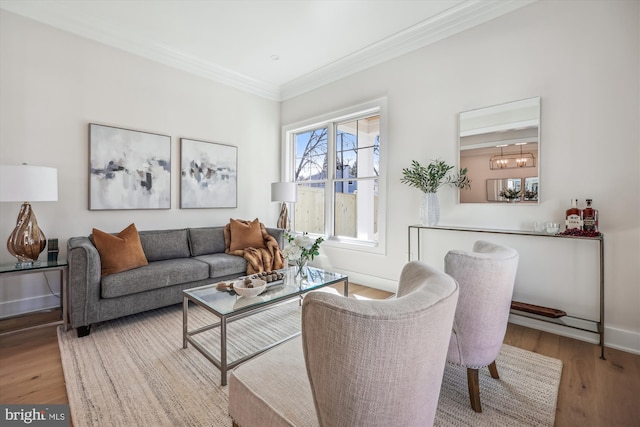 living room featuring a chandelier, ornamental molding, baseboards, and wood finished floors