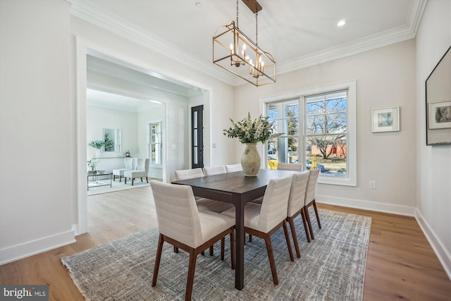 dining space with a chandelier, wood finished floors, baseboards, and ornamental molding