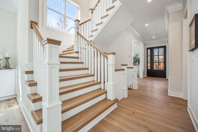 stairs with wood finished floors, recessed lighting, crown molding, baseboards, and a towering ceiling