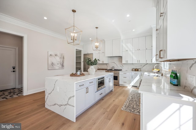 kitchen with a kitchen island, crown molding, high end range, white cabinetry, and a sink