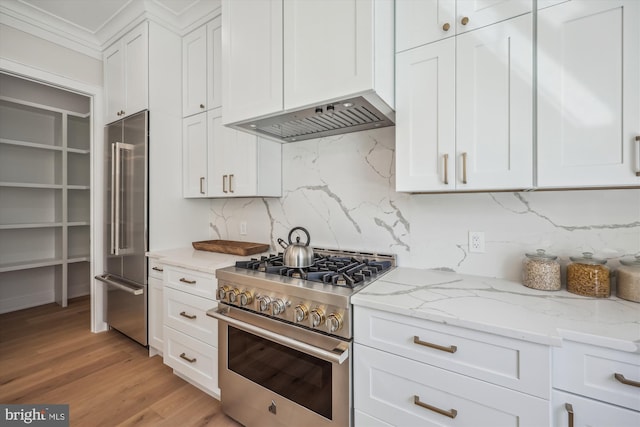 kitchen with white cabinets, light stone countertops, high quality appliances, and premium range hood