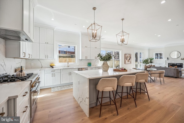 kitchen with a kitchen bar, light wood-style flooring, a kitchen island, stainless steel appliances, and crown molding