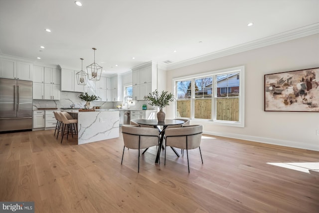 dining space featuring light wood finished floors, recessed lighting, baseboards, and ornamental molding