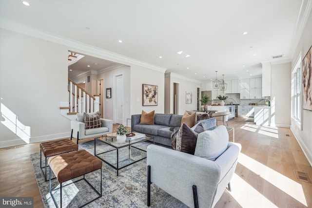 living room featuring visible vents, light wood-style flooring, stairs, and crown molding