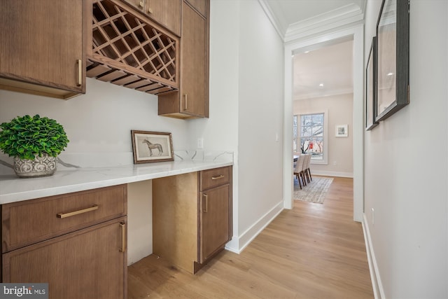 interior space featuring baseboards, light wood-type flooring, and ornamental molding