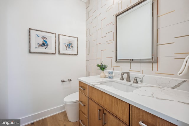 bathroom featuring toilet, vanity, baseboards, and wood finished floors