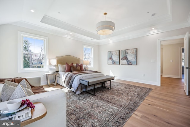 bedroom with a tray ceiling, ornamental molding, and light wood-style flooring