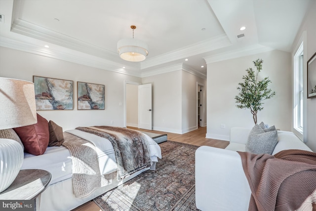 bedroom with a tray ceiling, crown molding, recessed lighting, and light wood-style floors