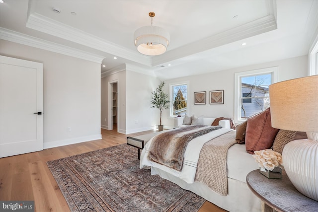 bedroom featuring multiple windows, a raised ceiling, light wood-style floors, and baseboards