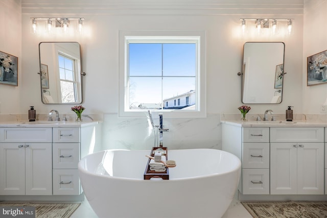 bathroom with a sink, a freestanding bath, tile walls, and two vanities