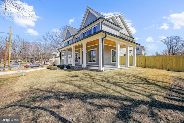 view of front facade featuring covered porch, a front lawn, and fence