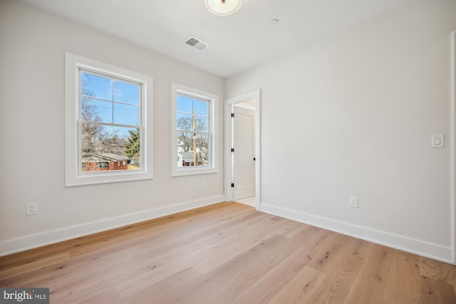 empty room featuring visible vents, baseboards, and light wood-style floors